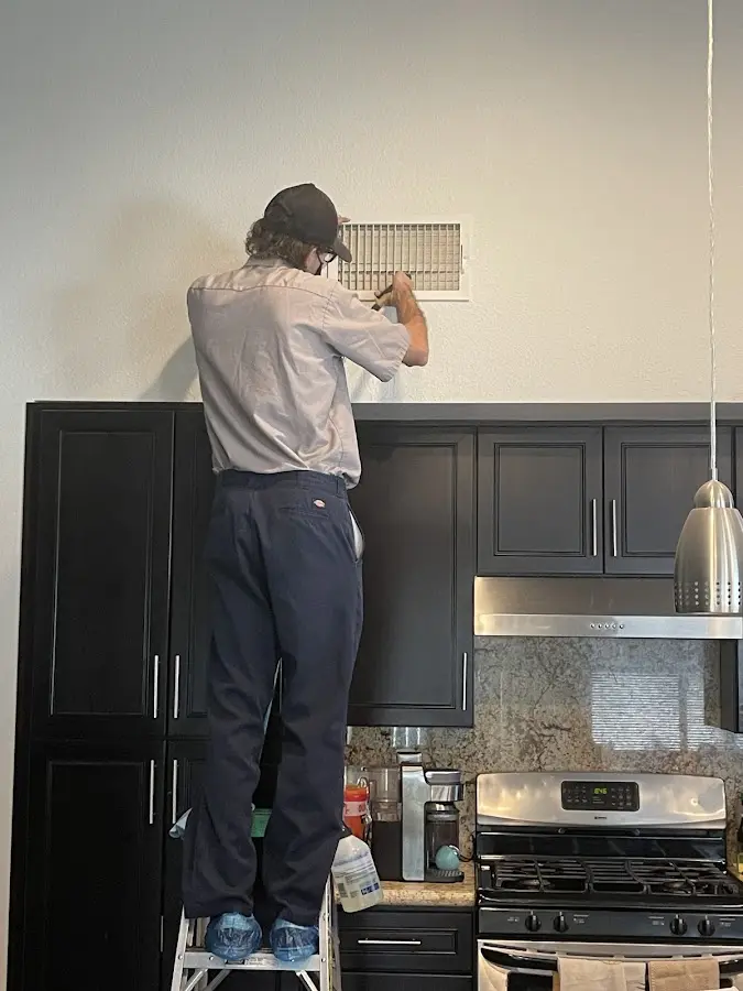 Technician inspecting an air vent during HVAC service in St. Rose